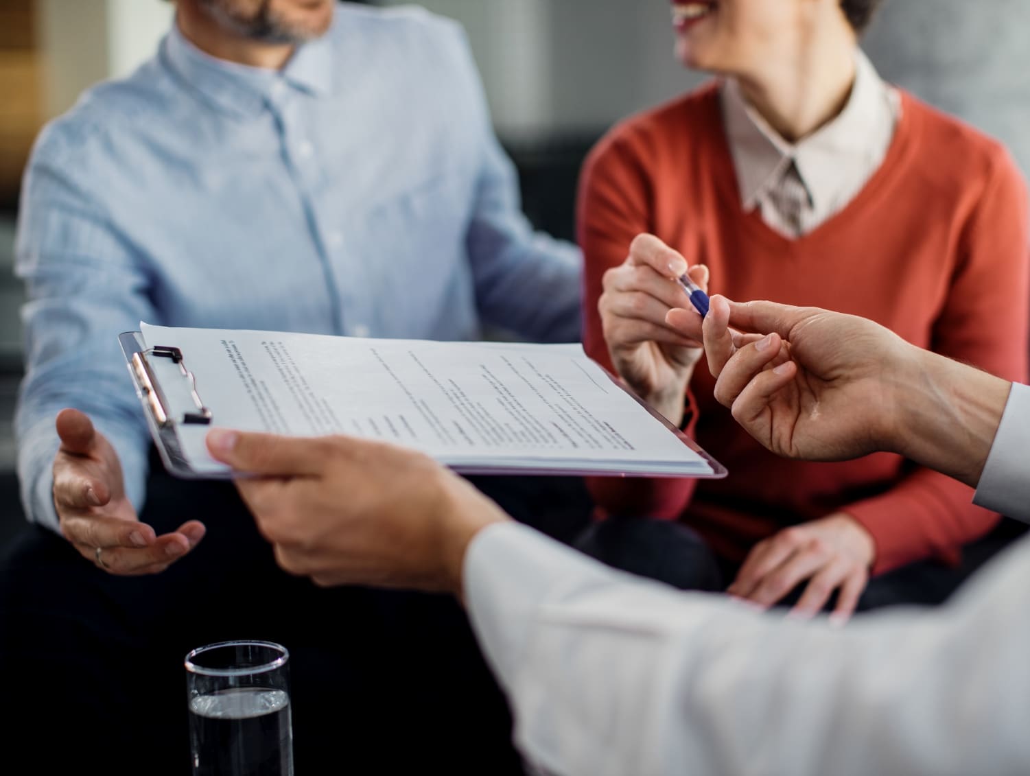 closeup unrecognizable couple signing contract with financial advisor